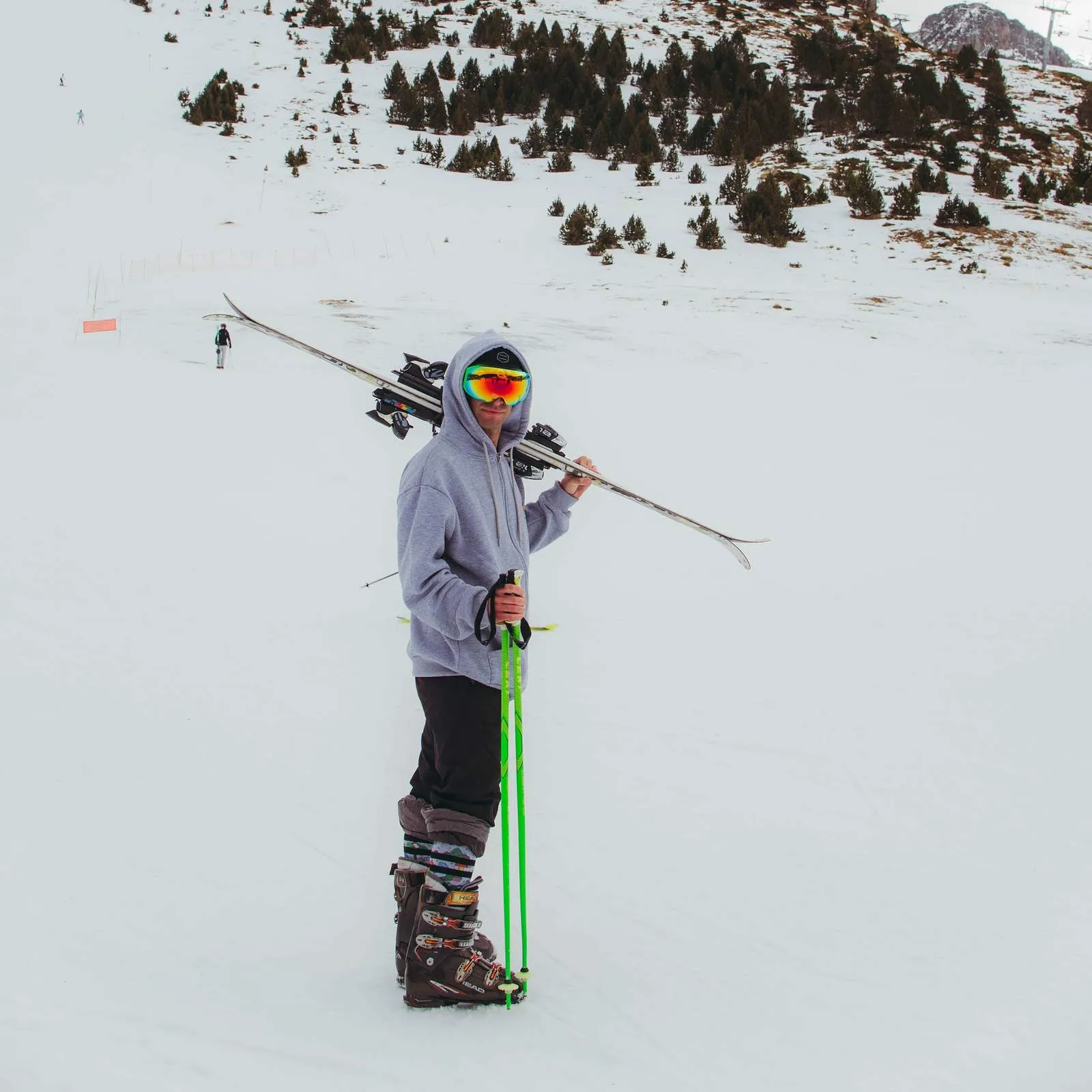 Uomo con sci, bastoncini da sci e occhiali da neve su una pista innevata. Indossa calzini da neve Leaf Me Alone.