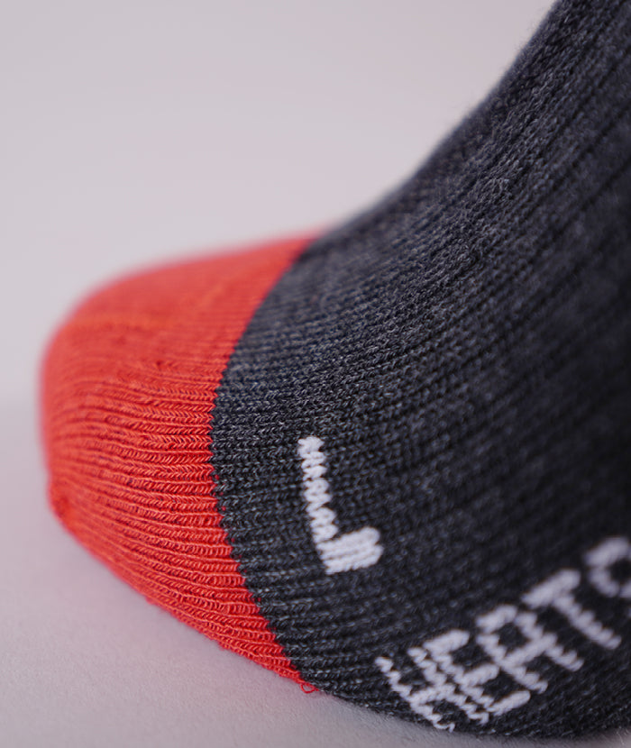 Detailaufnahme einer grauen Socke mit roter Spitze, einer weißen "L"-Kennzeichnung und dem Wort "HEAT".
