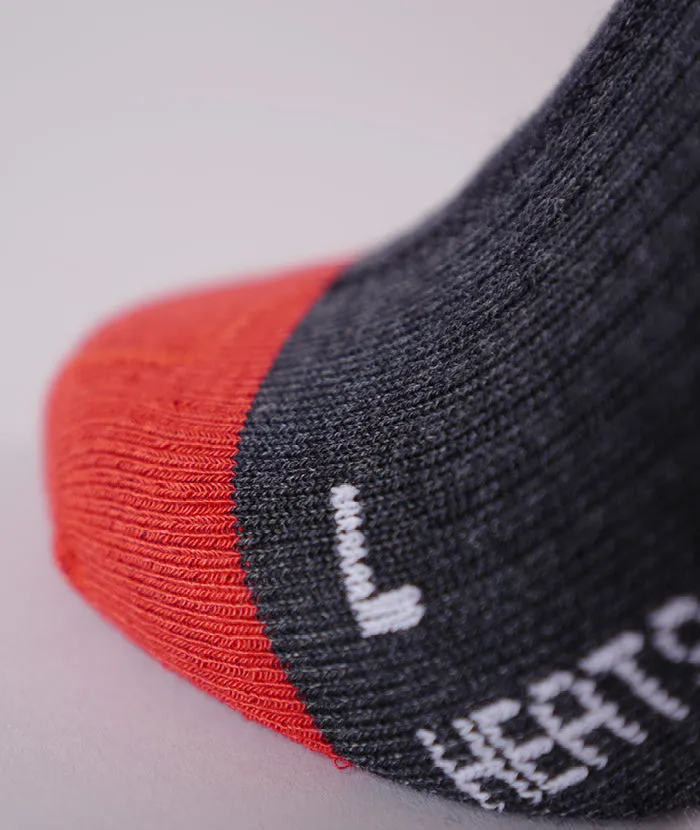Détail d'une chaussette grise avec une pointe rouge, un marquage blanc "L" et le mot "HEAT".