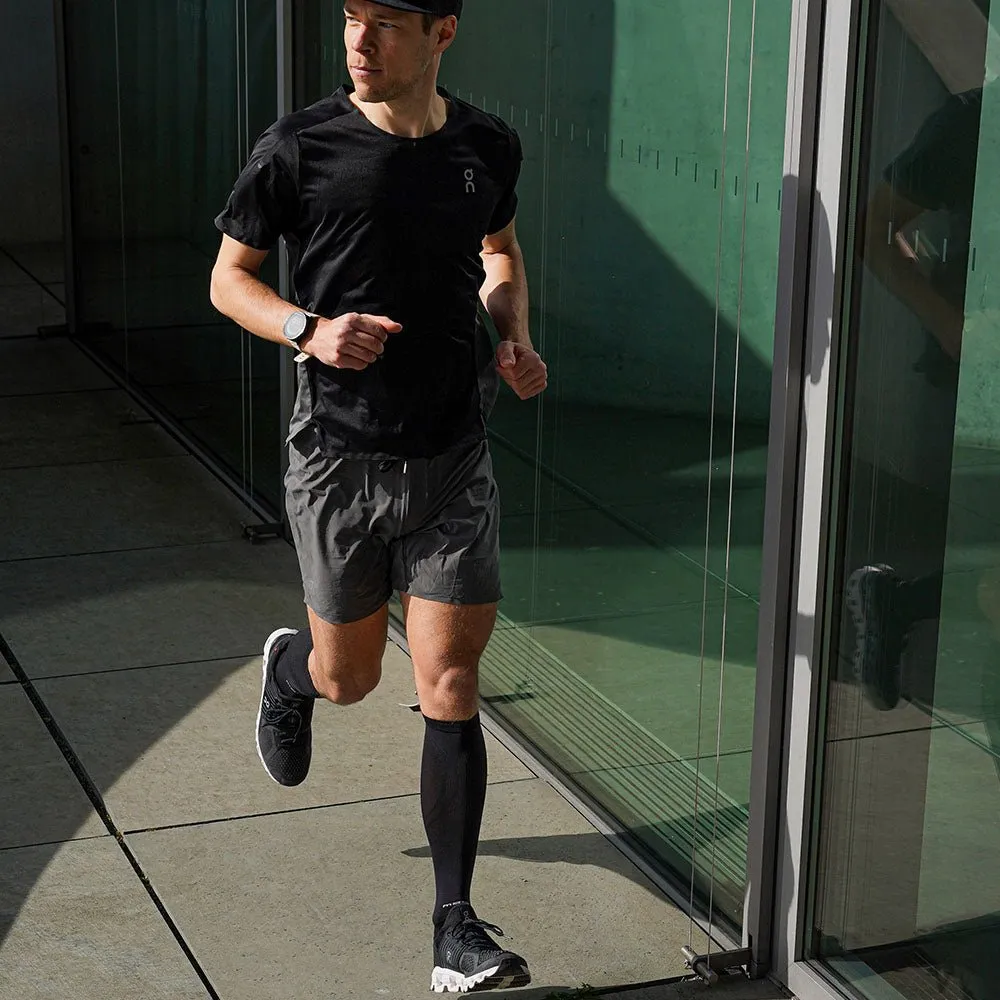 Runner with McDavid Elite Recovery compression socks, black running shoes, shorts and T-shirt while running.