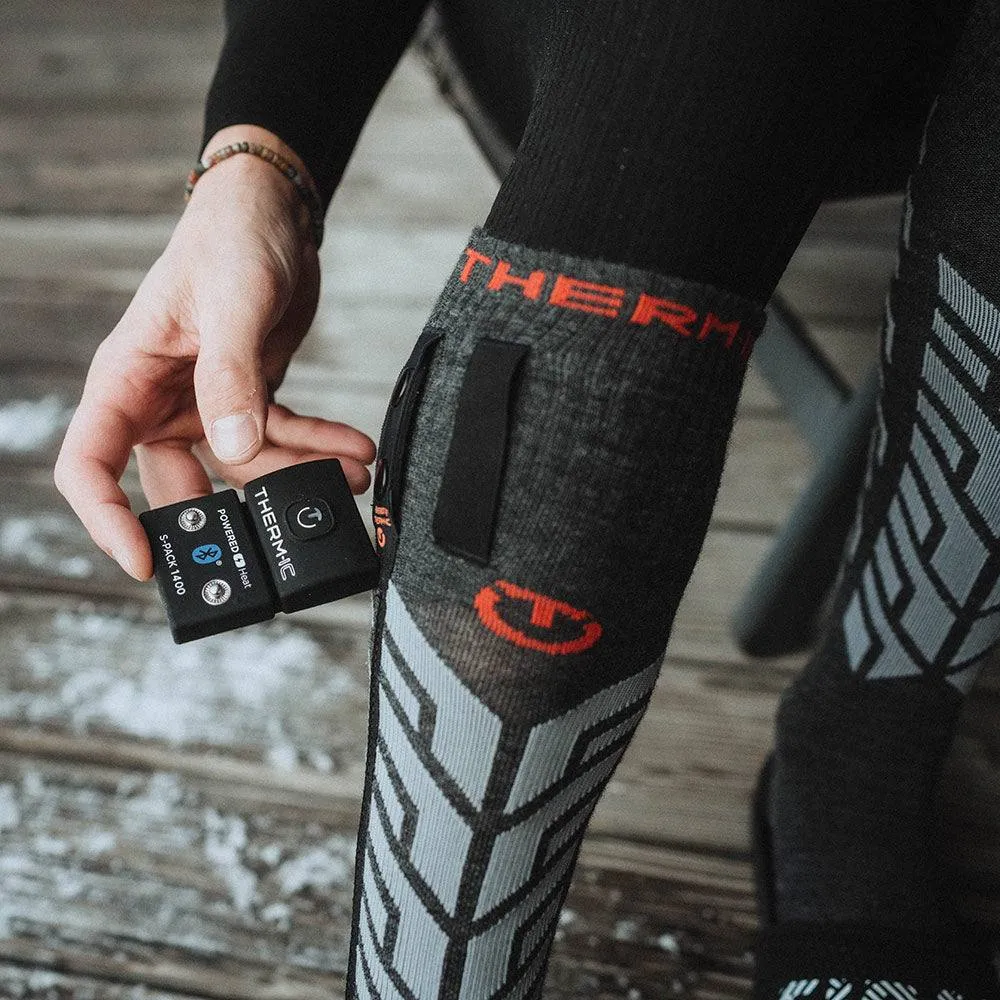 Persona che mostra la calza Thermic Ultra Warm con la batteria S-Pack 1400 in mano.