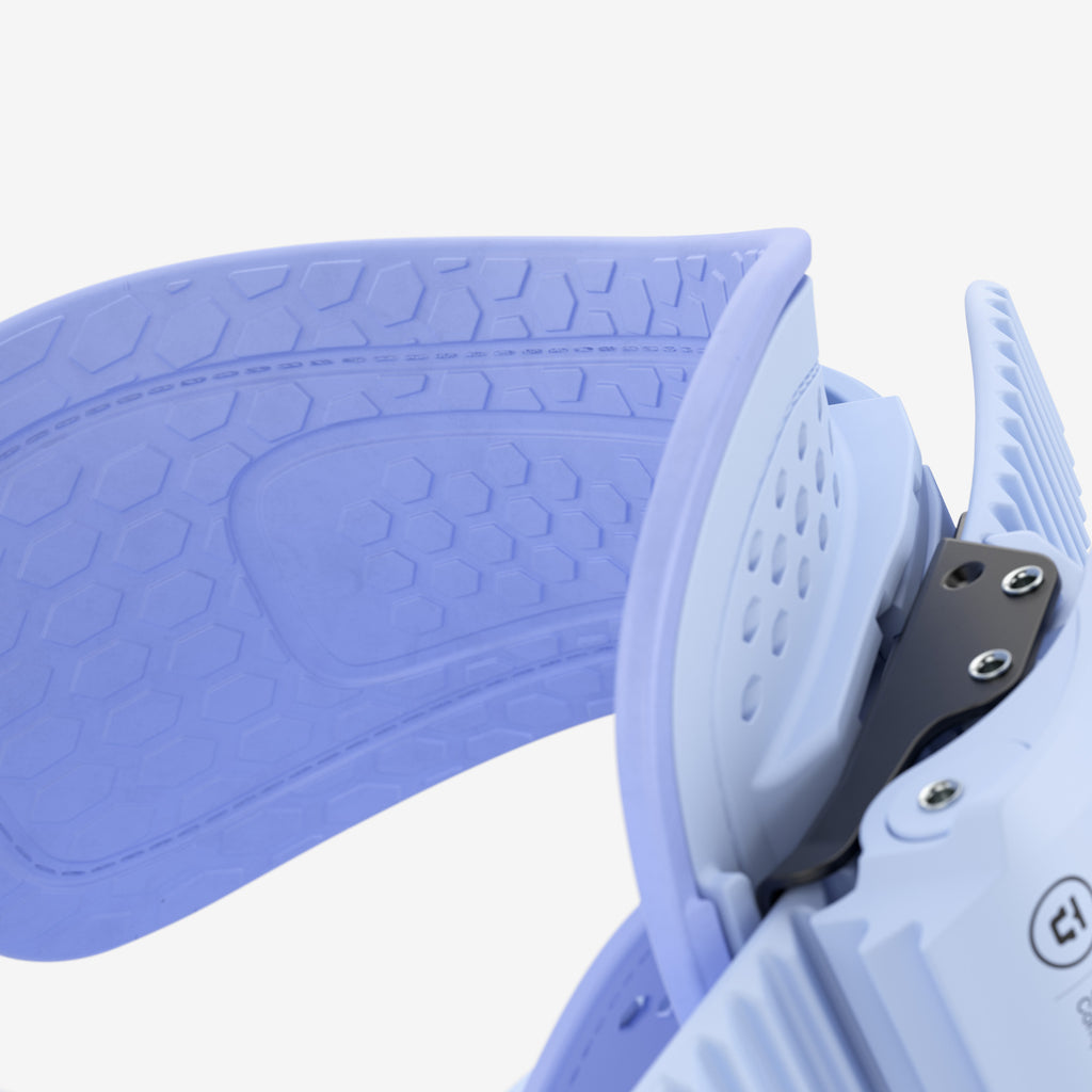 Détail d'une fixation de snowboard claire Détail d'une fixation de snowboard bleu clair et violet avec un motif en nid d'abeille, un design perforé et des vis métalliques.