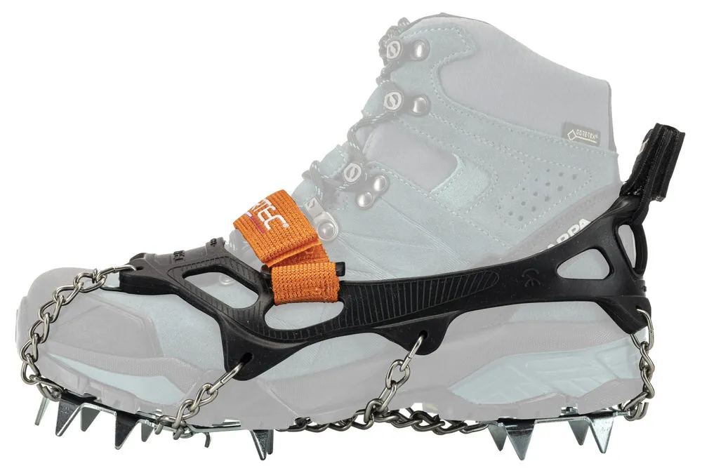 Profilansicht von einem Trekking-Schuh mit montierten Alp 2.0 Steigeisen. Die Schuhkrallen bestehen aus Ketten, Stahlplatten und einem orangefarbenen Riemen.