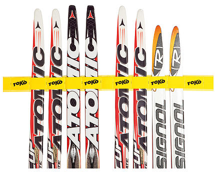 Langlaufski mit Toko Halter Mehrere Langlaufski, mit gelbem Toko Skiholder Belt zusammengehalten, frontal.