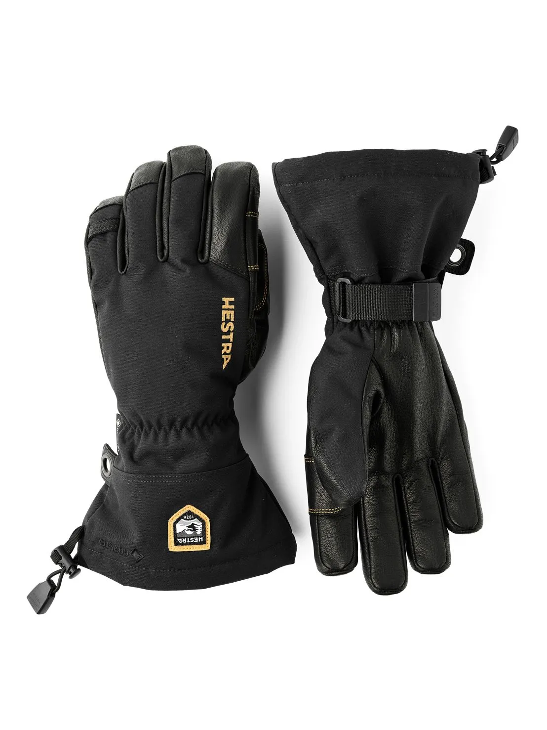 Zwei schwarze Hestra Gore-Tex 5-Finger-Handschuhe liegen auf einer weißen Oberfläche. Einer hat ein Hestra-Logo.