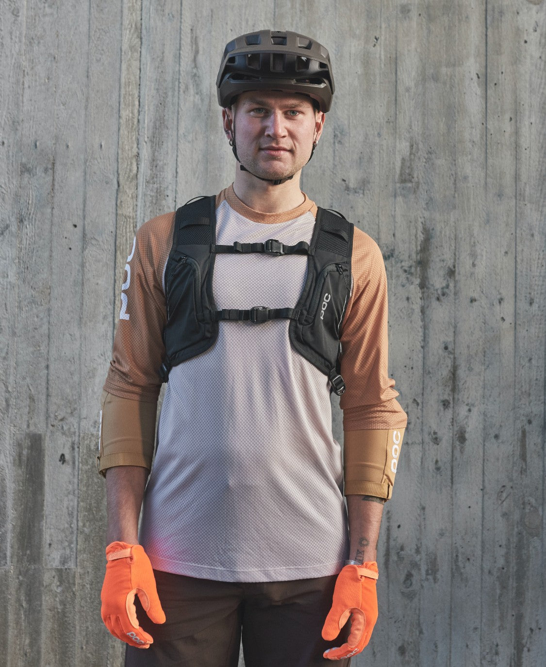 Mann mit Rucksack Mann mit Fahrradhelm, orange Handschuhen und Column VPD Backpack. Der Rucksack hat zwei Brustgurte.
