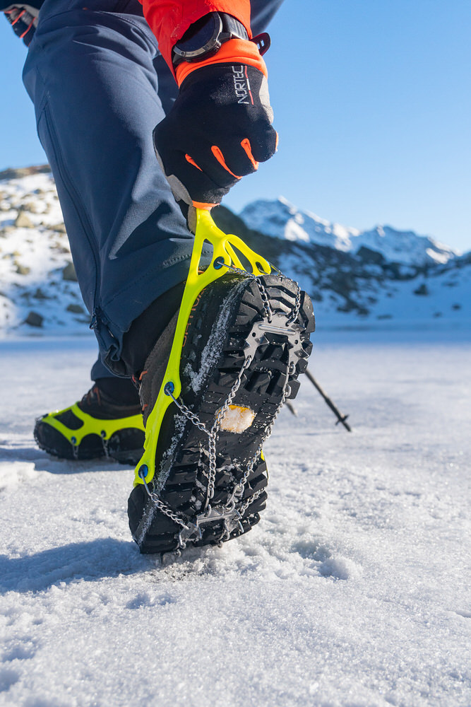 Schuhkralle für Schnee Schuhkralle am Schuh auf Schnee befestigt. Die Schuhkralle hat gelbe Elastomer und Steigeisenplatten.