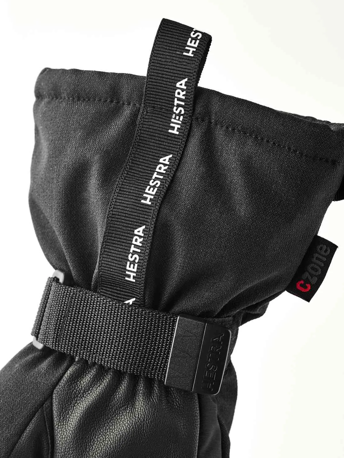 Nahaufnahme eines schwarzen Hestra-Handschuhs mit Stoffschlaufe und Handgelenksband. Das CZone-Logo ist sichtbar.
