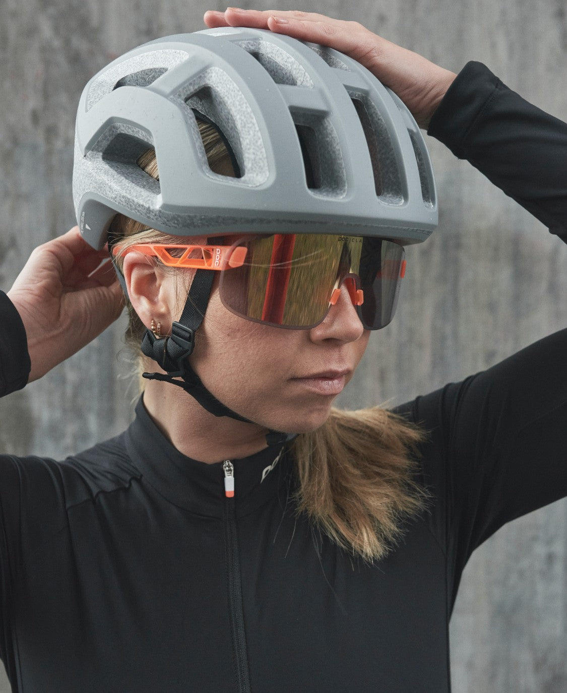 Fahrerin mit POC Elicit Fahrerin mit grauem Helm und orangefarbener POC Elicit Sonnenbrille mit Gold Mirror Glas.