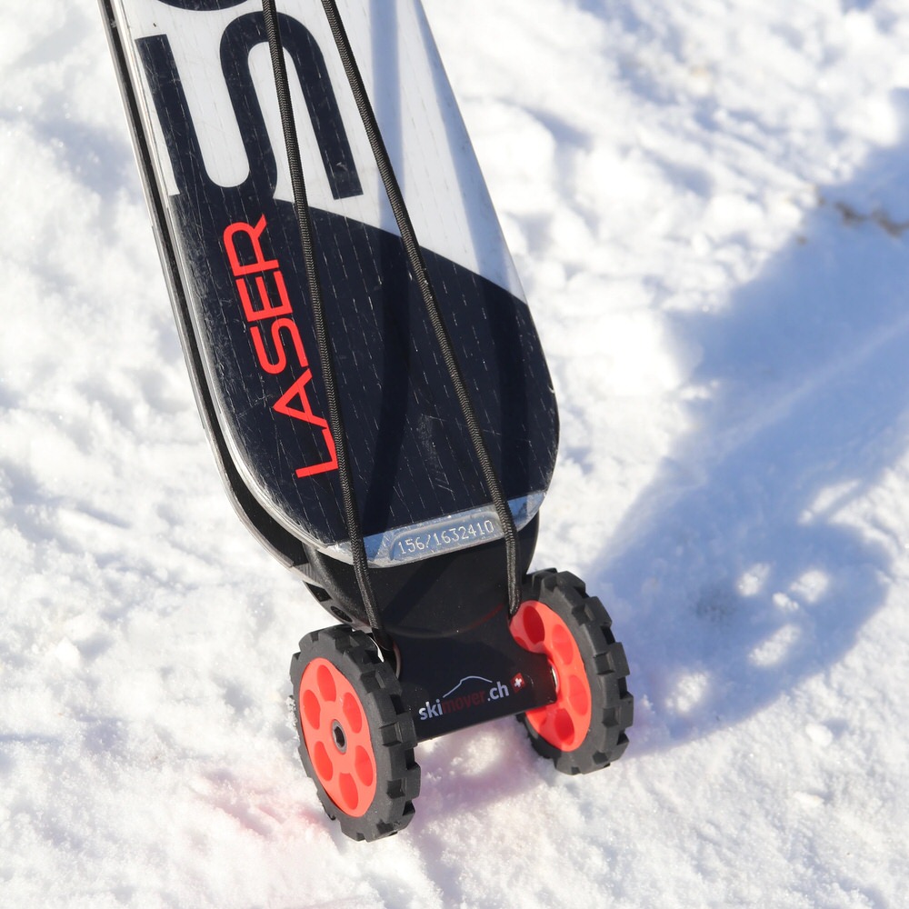 Ski mit montiertem, rotem Skimover Easy auf Schnee. Der Skimover hat zwei Räder. Das Ski-Ende ist schwarz-weiss.