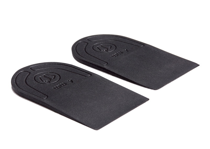 Zwei schwarze, keilförmige Schuheinlagen aus Gummi liegen auf weißem Grund. Auf der Oberseite befindet sich ein erhabenes Logo.