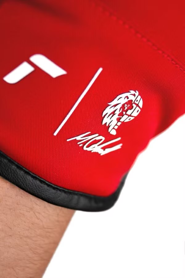 Reusch Marco Odermatt Handschuh Nahaufnahme eines roten Reusch Marco Odermatt Handschuhs mit weißem Logo und schwarzem Lederdetails.