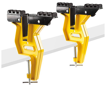 Supports jaunes pour snowboards Deux supports jaunes pour snowboard (Board Grip 2.0) avec un dispositif de fixation noir sont fixés sur une surface blanche.