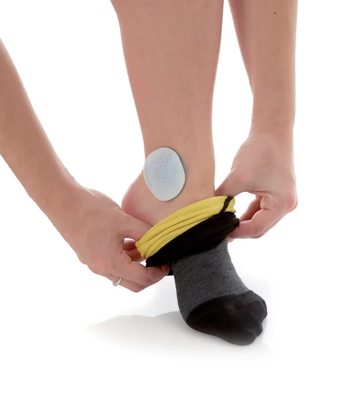 Person pulls sock over ankle. A round ankle protector can be seen on the ankle.