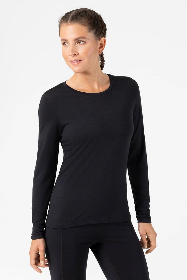 Eine Frau trägt ein schwarzes Super.Natural Base Crew Neck 230 Langarmshirt und eine Leggings.