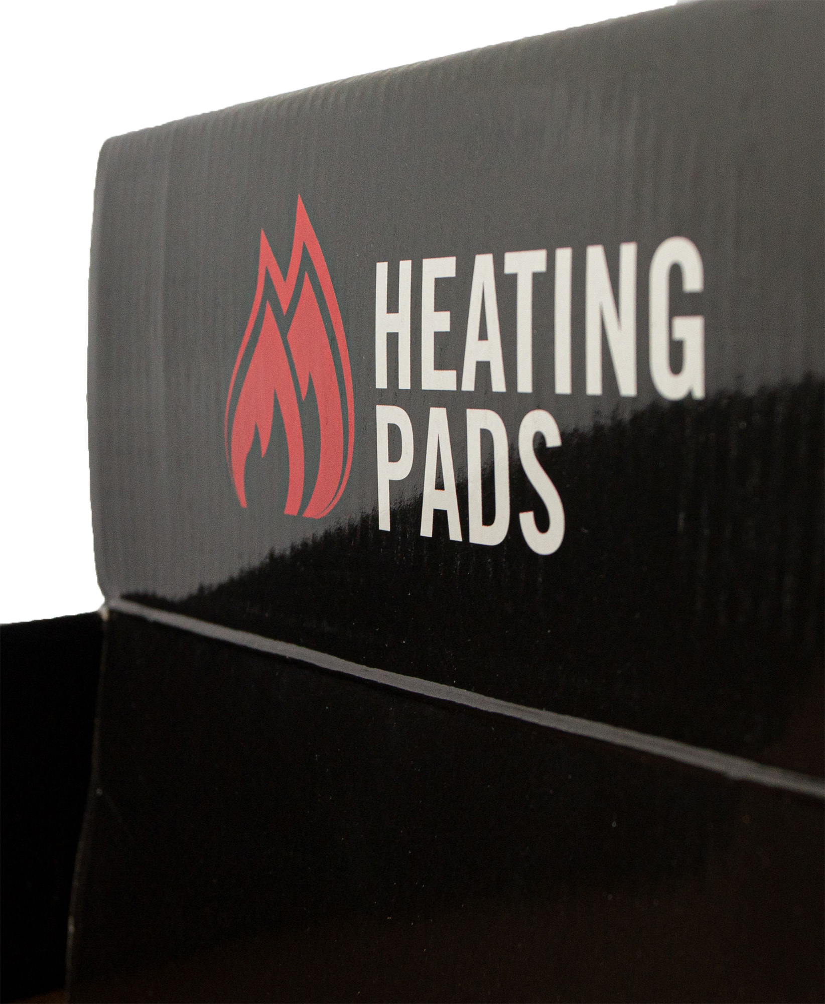 Emballage en carton noir, inscription "HEATING PADS" en blanc, symbole de flamme rouge à côté.
