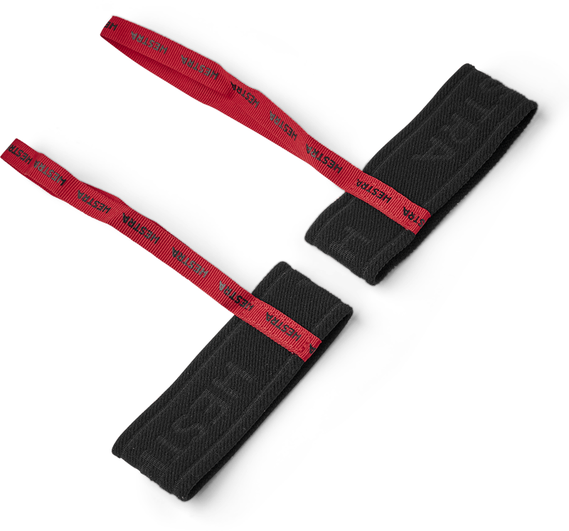 Deux manchettes en tissu noir avec un ruban rouge sur lequel est écrit "Hestra" sont posées en diagonale sur un fond blanc.