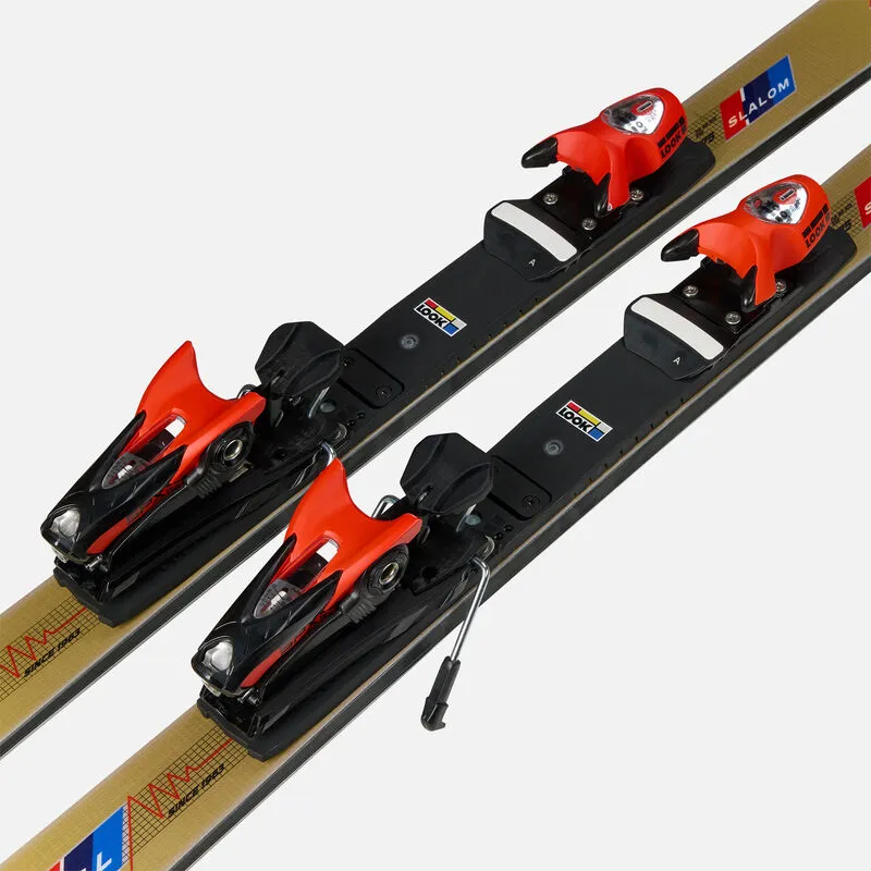 Two slalom skis with gold-colored surface and red/black bindings on a white background.