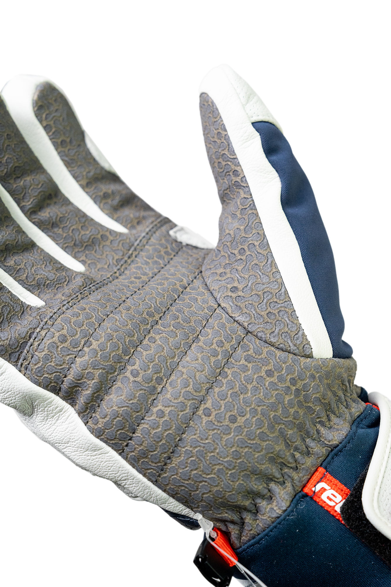 Gros plan sur un gant à la paume grise, aux rayures blanches sur les doigts et au tissu bleu marine.
