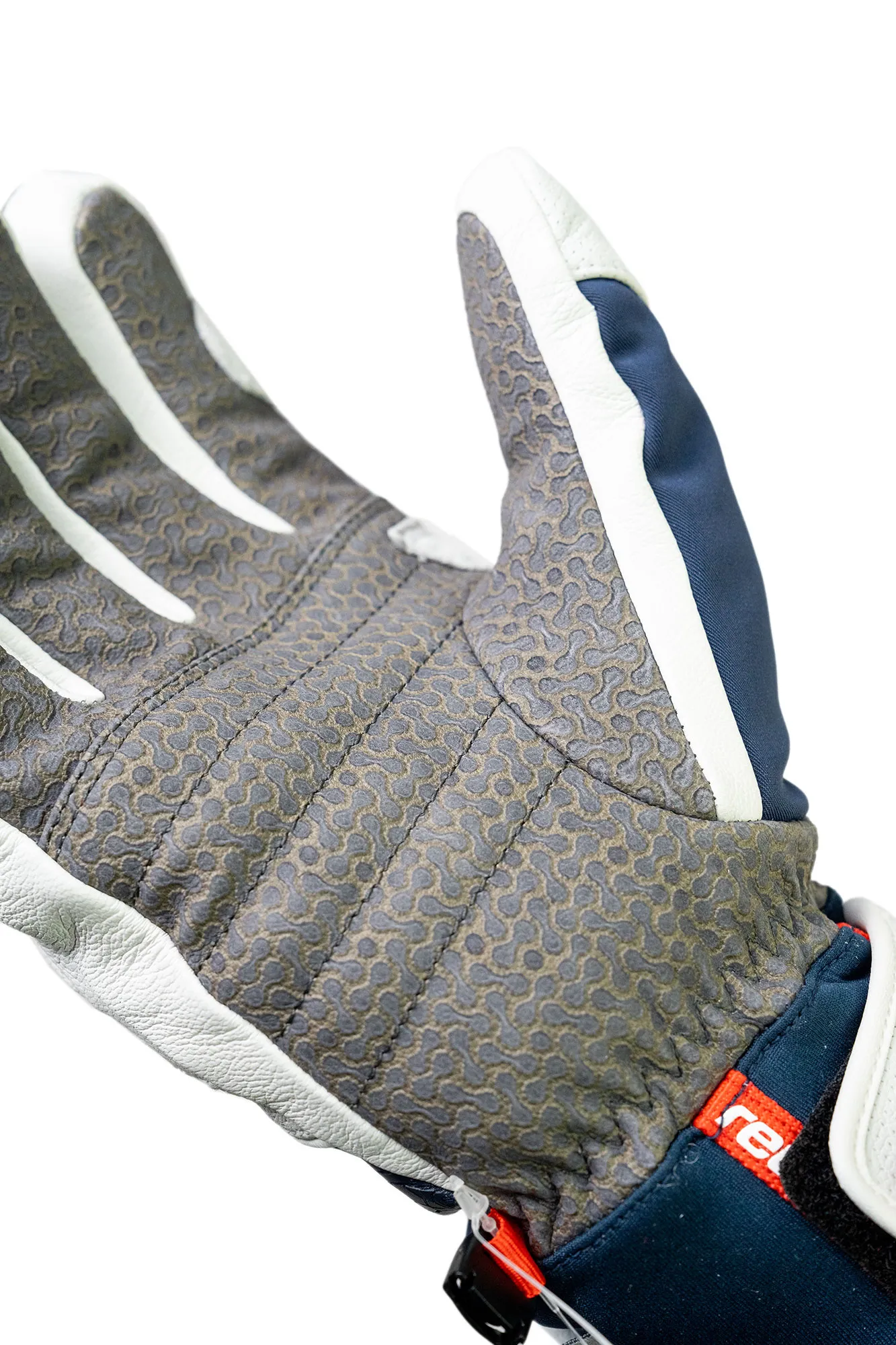 Primo piano di un guanto con palmo grigio, strisce bianche sulle dita e tessuto blu navy.