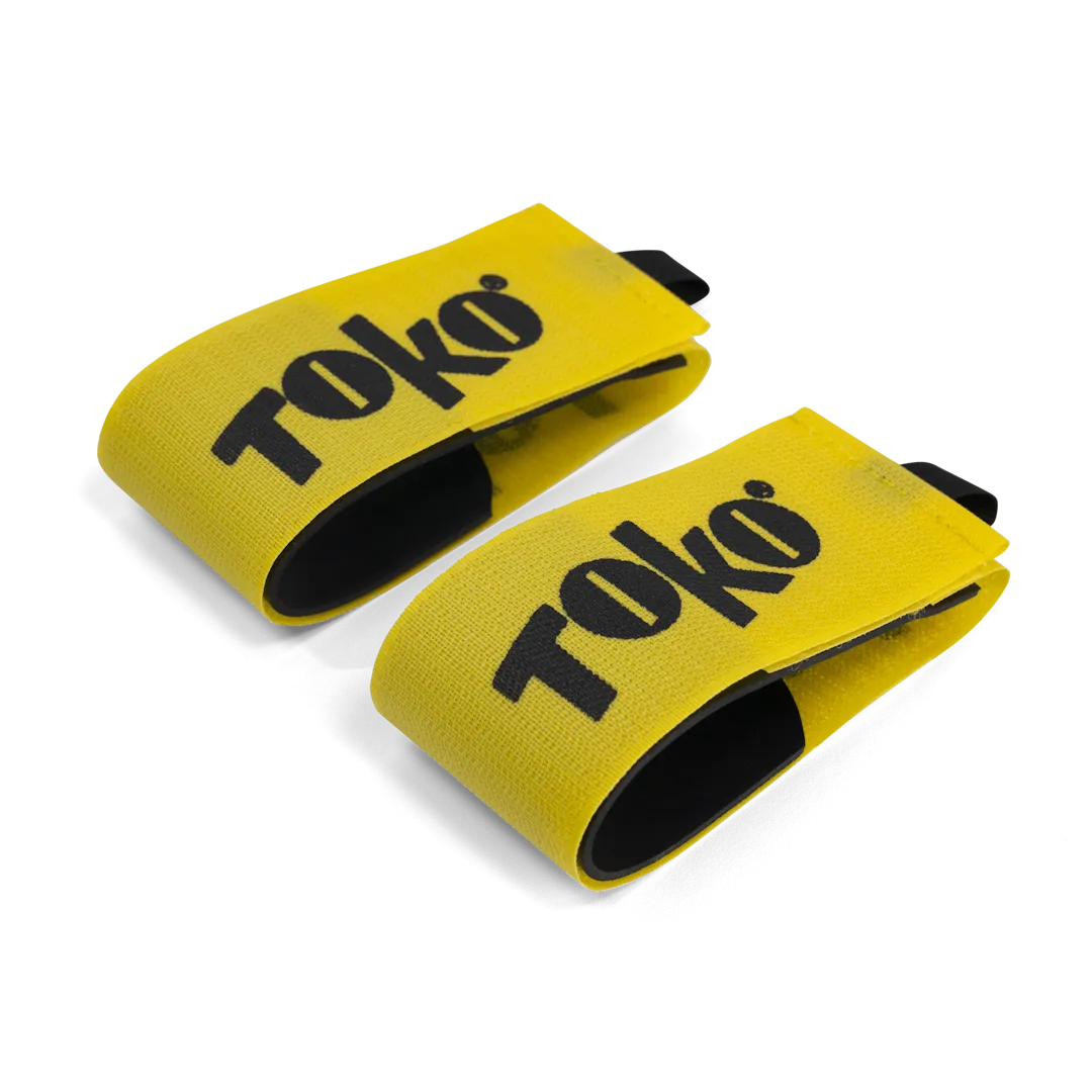Two yellow Toko ski clips with black lettering and black lining on a white background.