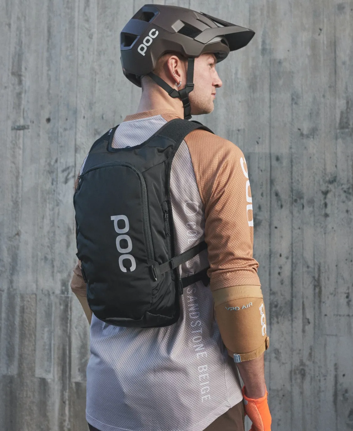 Ein Mann mit Fahrradhelm trägt einen schwarzen Column VPD Backpack 13L.