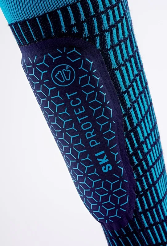 Nahaufnahme von Sidas Ski Protect Skisocke mit Schienbeinschutz, blauen geometrischen Mustern und "SKI PROTECT" Schriftzug.