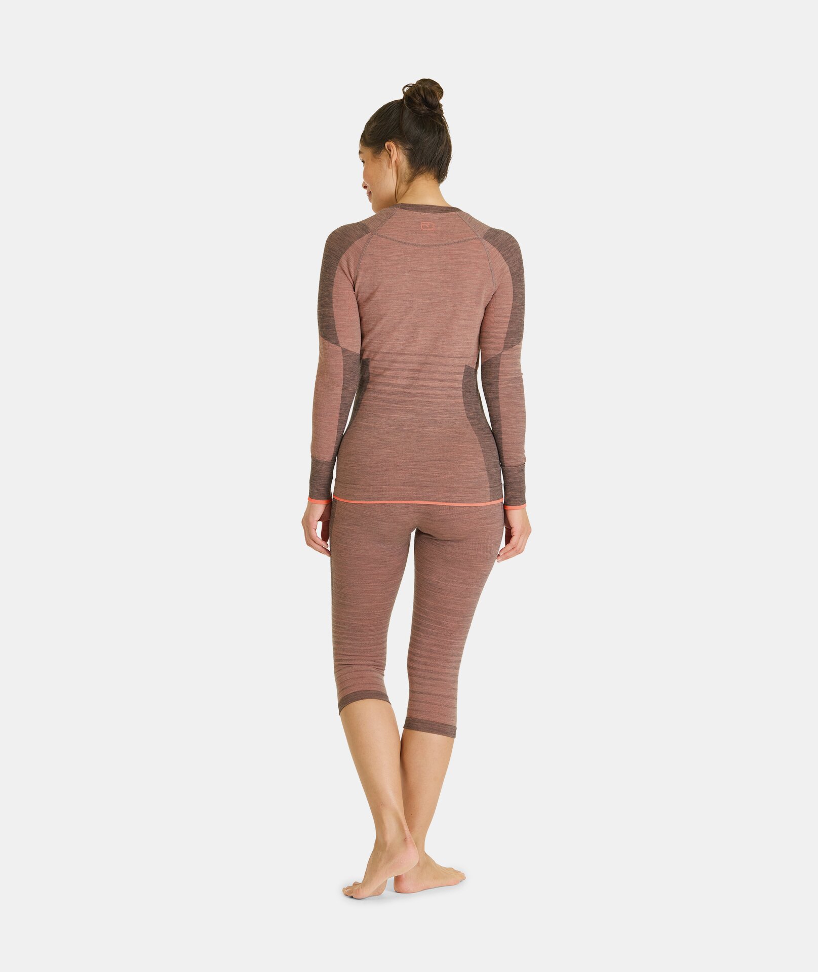 Frau von hinten, trägt bloomfarbene Ortovox 230 COMPETITION SHORT PANTS und ein Langarmshirt.