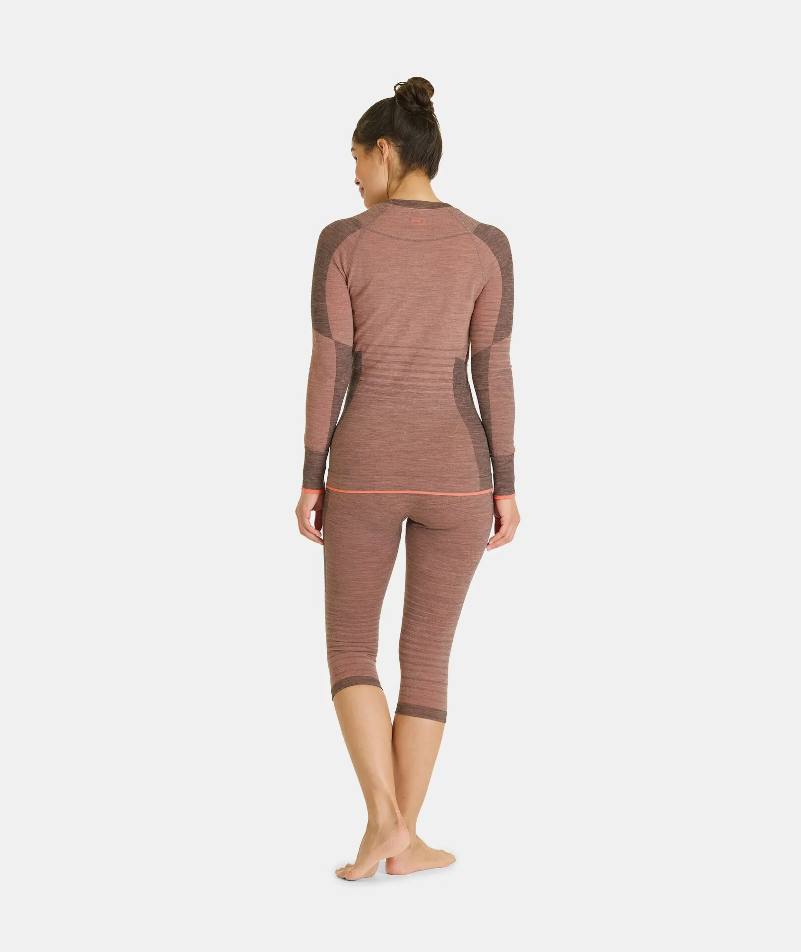 Woman from behind, wearing bloom-colored Ortovox 230 COMPETITION SHORT PANTS and a long-sleeved shirt.