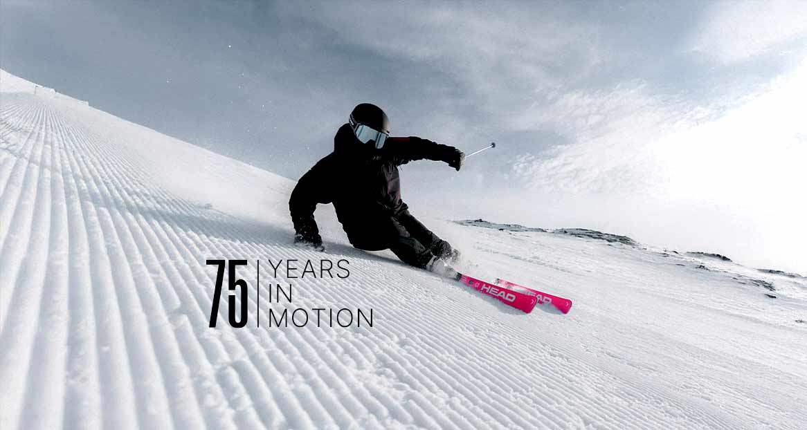 Ein Skifahrer in schwarzer Kleidung fährt eine präparierte Piste hinunter, im Vordergrund Text: "75 Years in Motion".