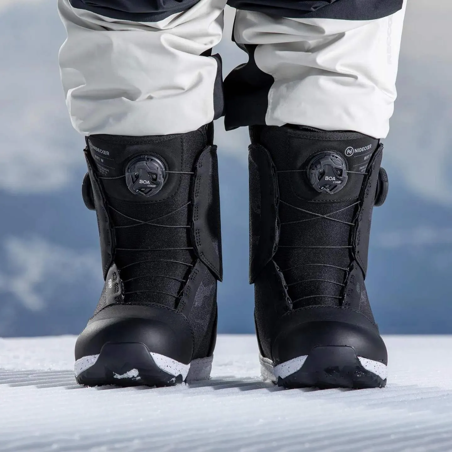 Chaussures de snowboard noires Nidecker Rift W avec système BOA sur neige, portées en partie par une personne.