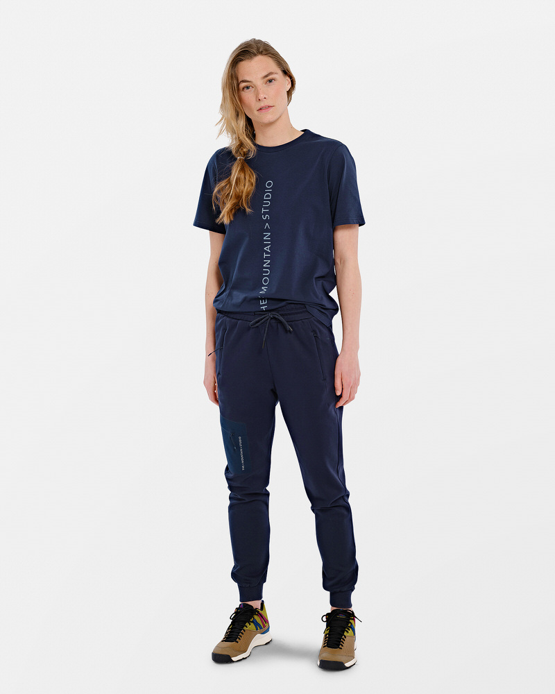 Personne portant un T-shirt bleu marine avec un logo vertical et un pantalon assorti.