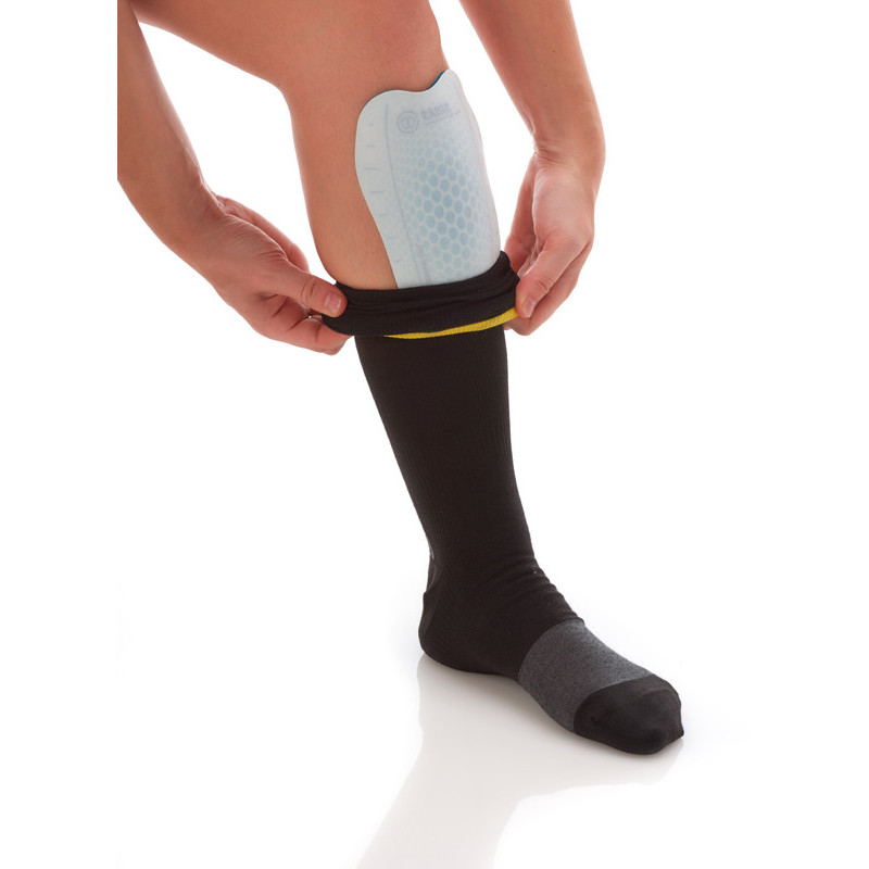 Person zieht Sidas Shin Gel Pad über Schienbein, schwarze Socke wird hochgezogen. Gel Pad mit Wabenmuster sichtbar.
