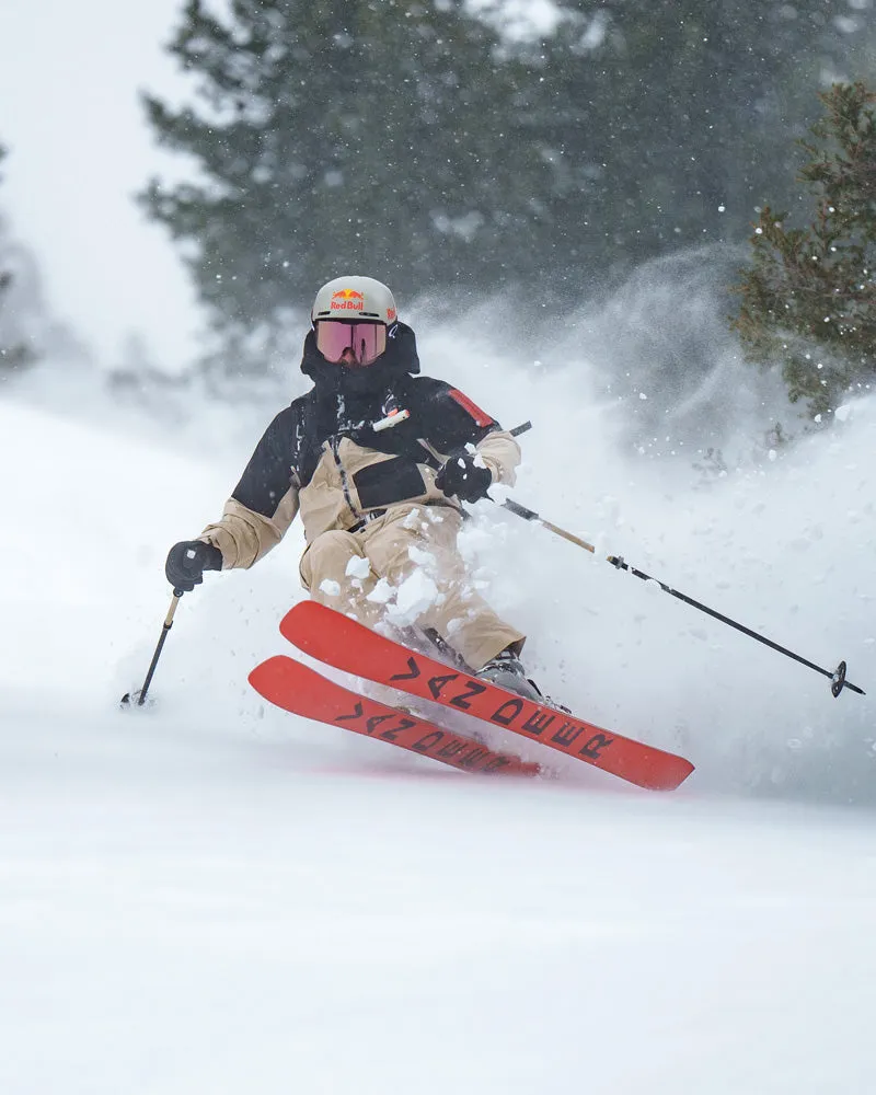 Skieur dans la neige profonde avec un ski rouge Van Deer et une fixation Look en mouvement. La neige gicle.
