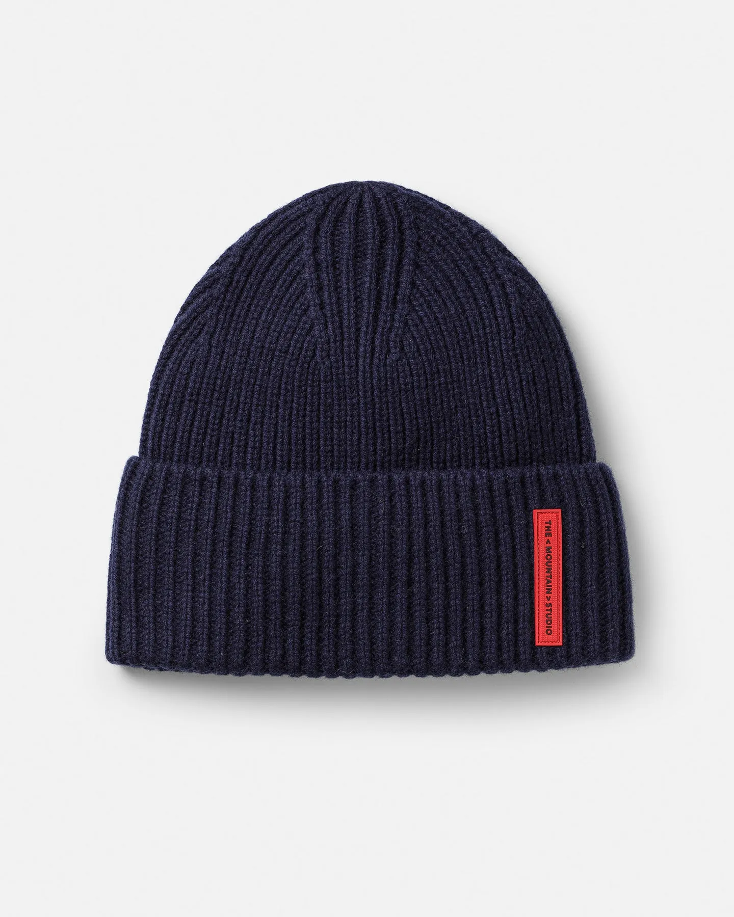 Cappello di lana a coste blu scuro su sfondo bianco. Al cappello è applicata un'etichetta rossa.
