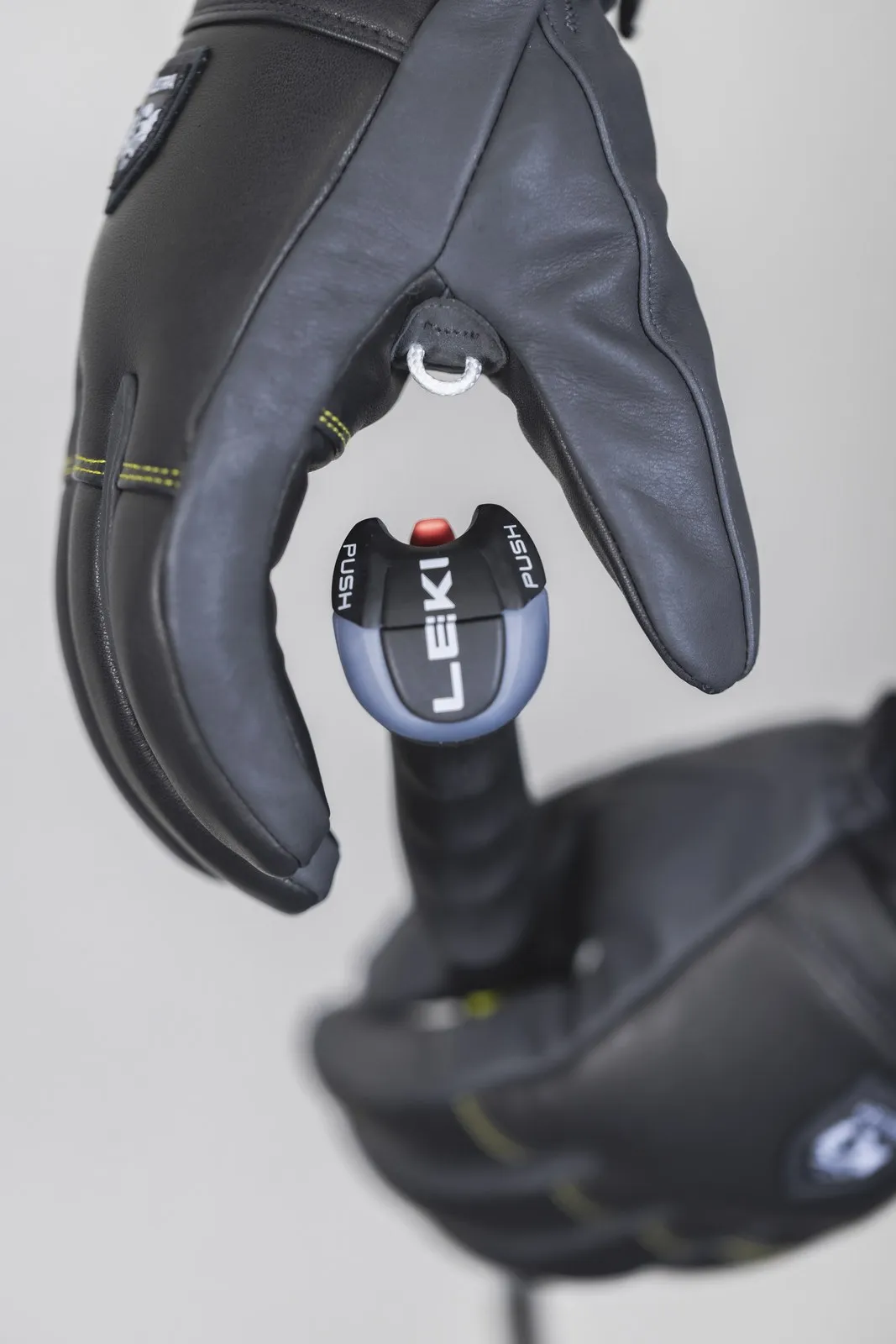 Guanto nero Hestra Omni Trigger con sistema Leki Trigger attaccato al bastoncino da sci. Primo piano del cinturino da polso.