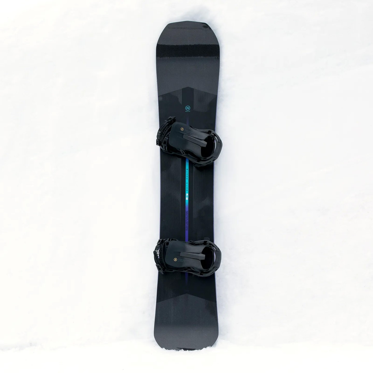 Nidecker Blade Plus Snowboard Dunkles Nidecker Blade Plus Snowboard mit montierten Bindungen liegt auf weißem Schnee.