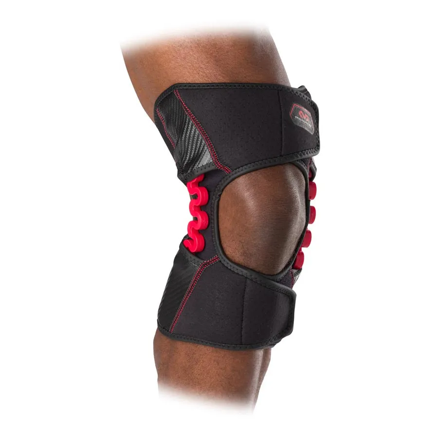Close-up: Knee support MCDavid NRG Knee Over Wrap 30590 with red joint and black fabric on a person's leg.