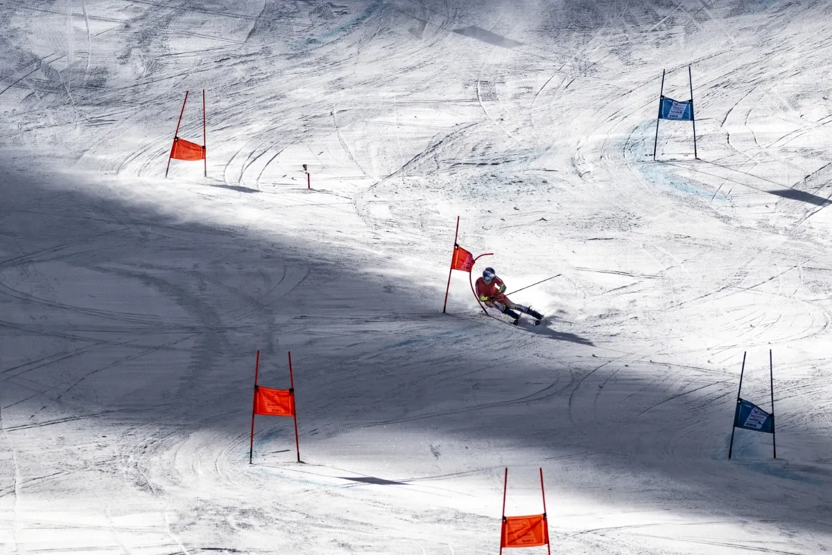 A skier skis down a snowy slope, passing red and blue flags.