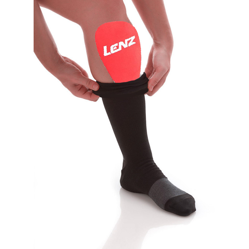 Eine Person zieht eine schwarze Socke über ein rotes Lenz Schienbein Gel Pad.