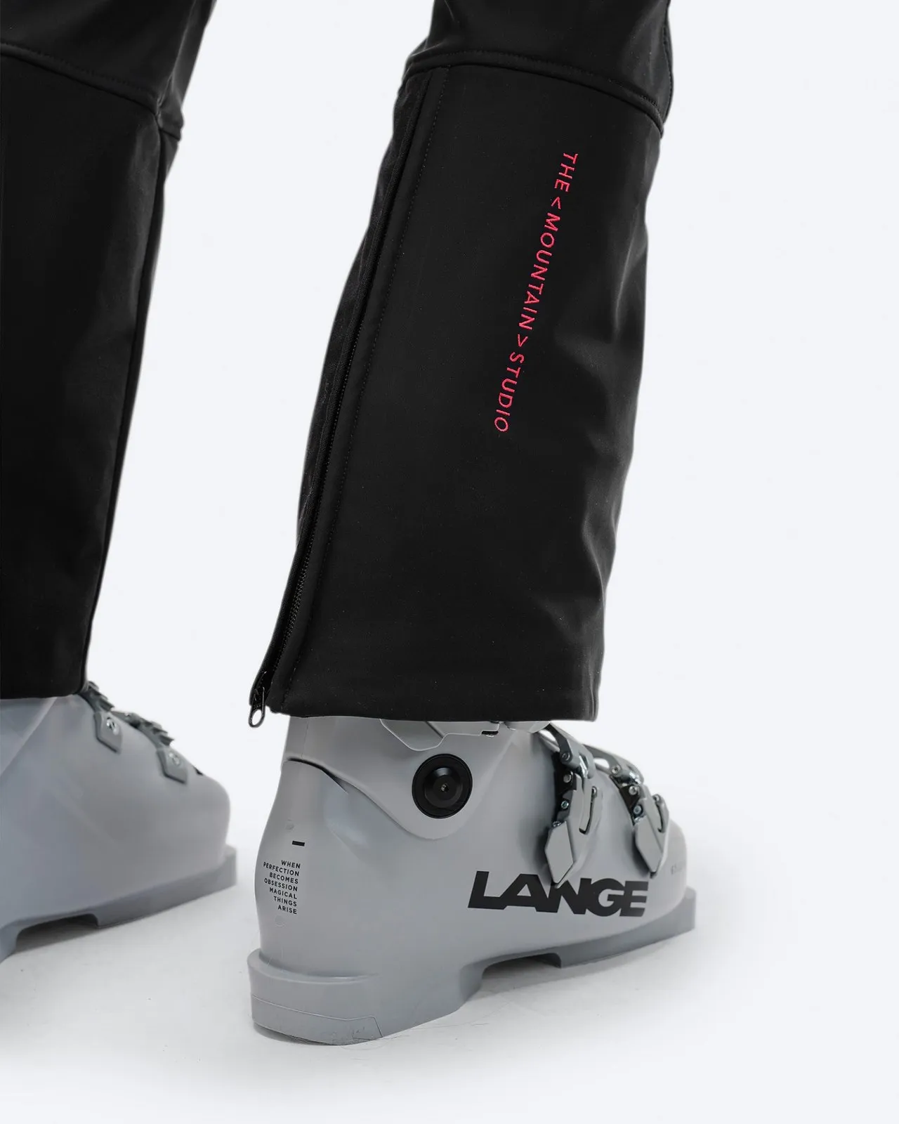 Detailaufnahme der schwarzen P-4 W 2L Stretch Ski Pants mit Ski-Schuh. Reißverschluss am Beinabschluss und Logo sichtbar.