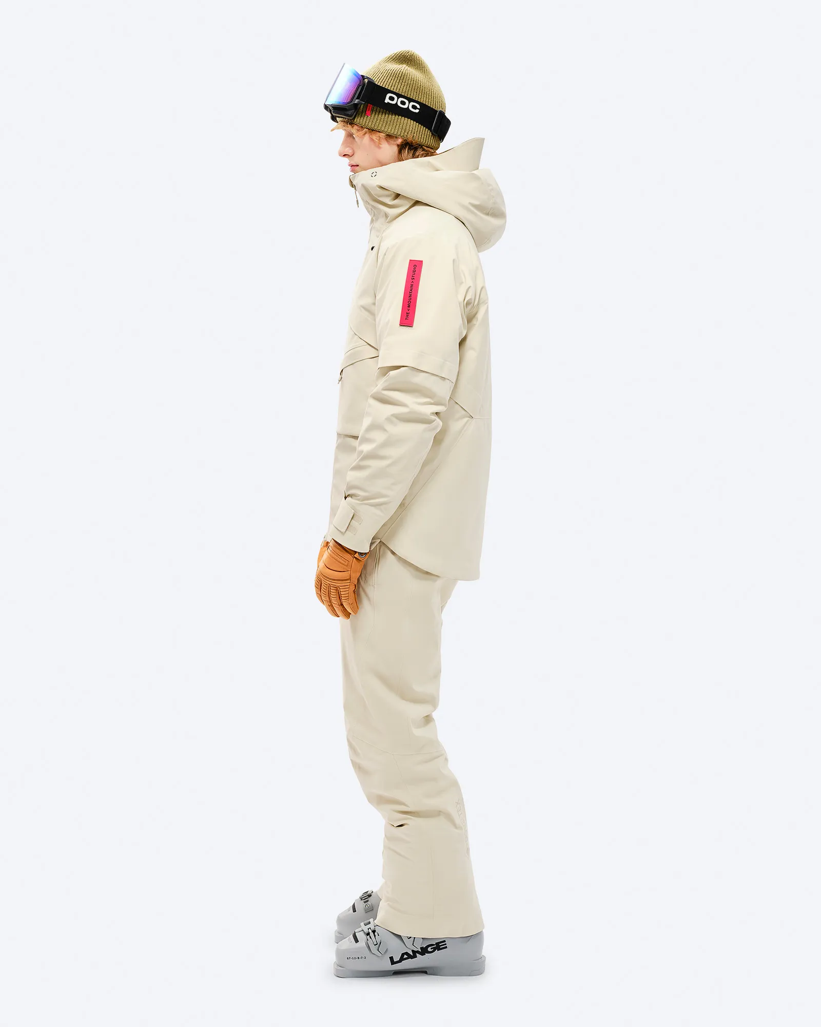 Person with ski equipment in beige GORE-TEX 2L Stretch Insulated Jacket from the side on a white background.