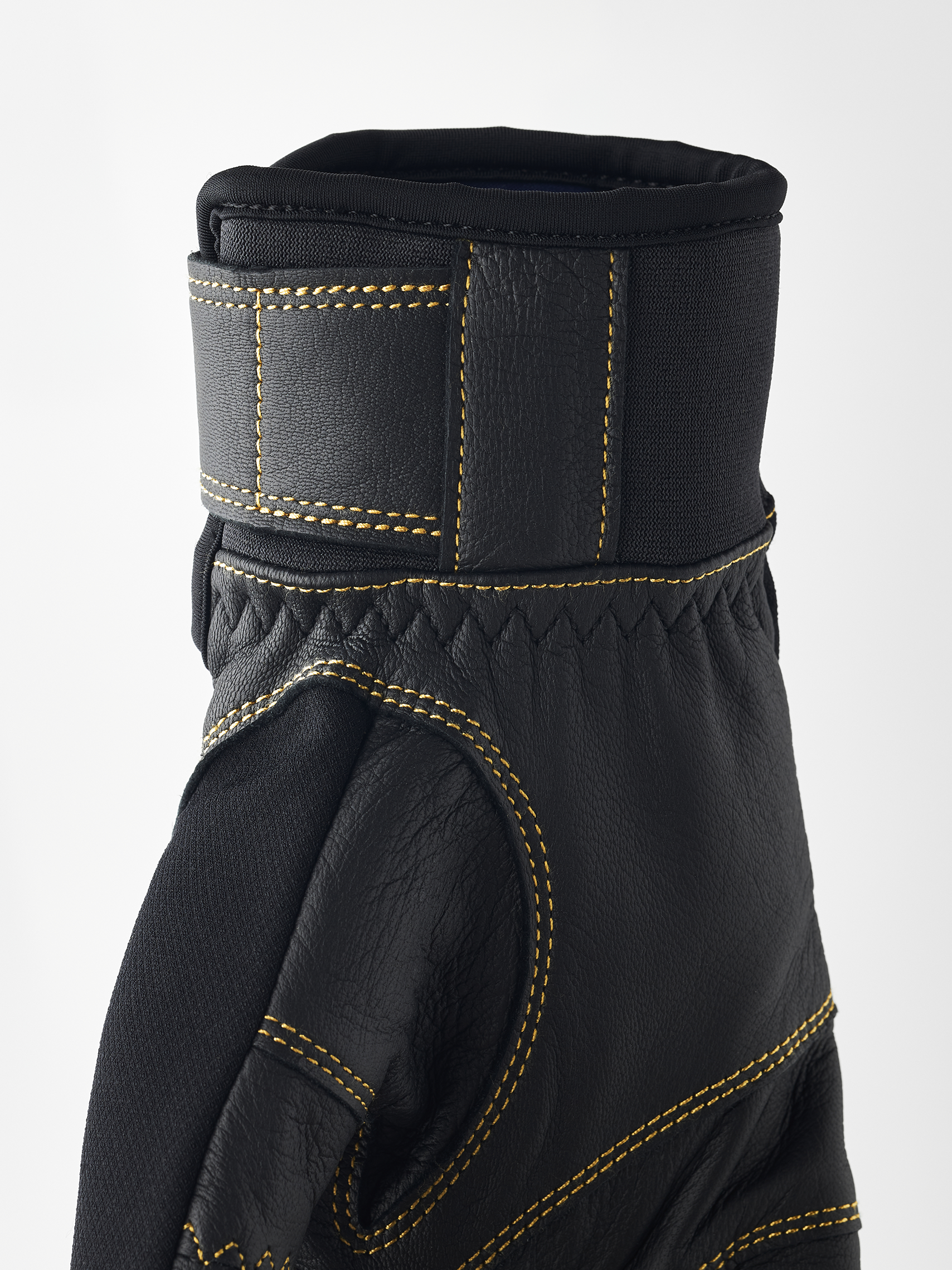 Gros plan sur un gant noir Hestra Ergo Grip Active avec des coutures jaunes.
