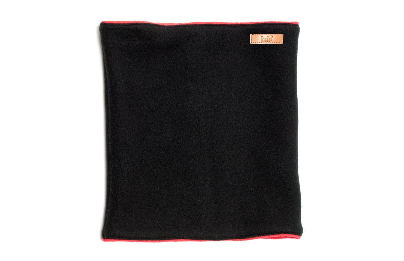Schwarzer, wendbarer Neckwarmer mit rotem Rand und kleinem, rechteckigen Logo-Patch oben rechts.