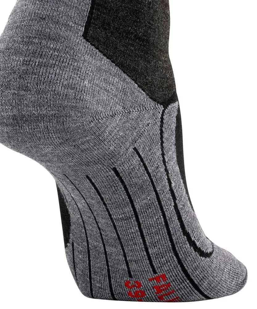 Chaussette de sport grise avec des touches noires sur fond blanc. Talon et bord supérieur noirs, avec des lignes verticales côtelées sur la voûte plantaire. Tissu gris chiné avec différentes structures de tricot. Marquages rouges visibles en bas.