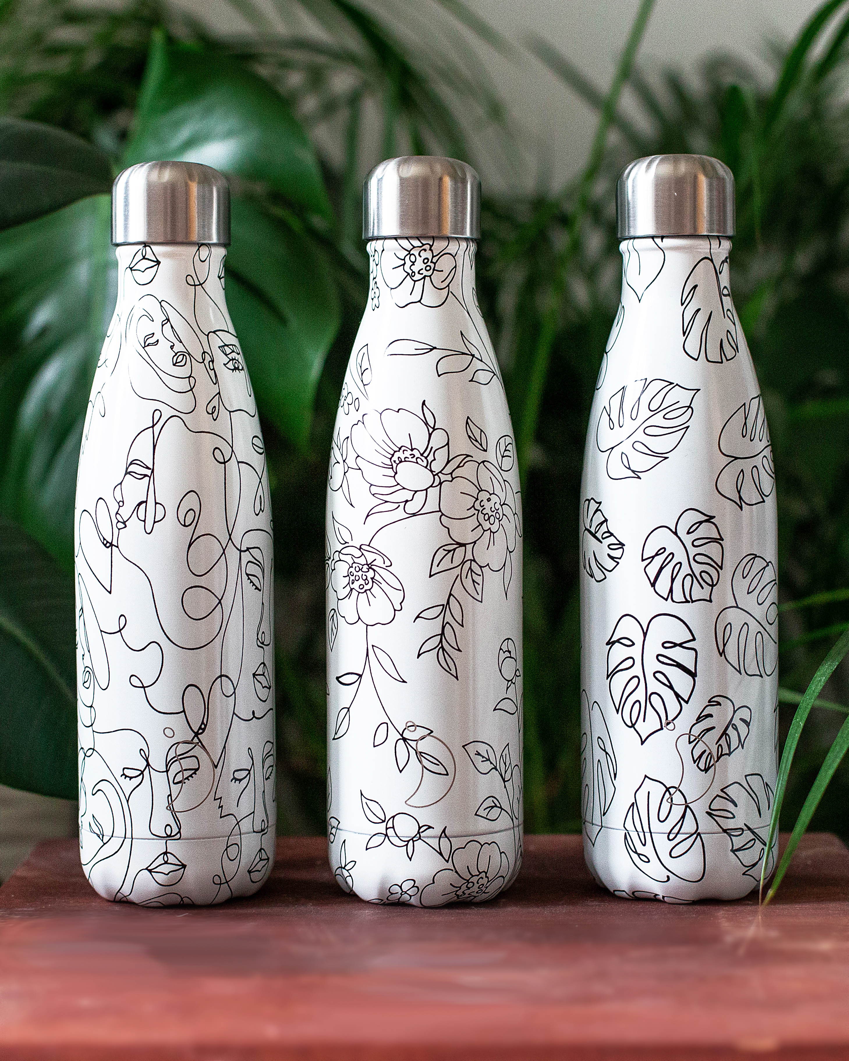 Drei Chillys Trinkflaschen mit Line-Art: Gesichter, Blumen und Blätter.