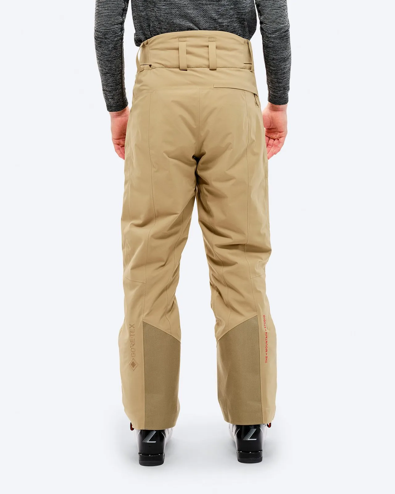 Rear view: Person wearing sand-colored P-1 GORE-TEX 2L Stretch Insulated Pant, ski boots.