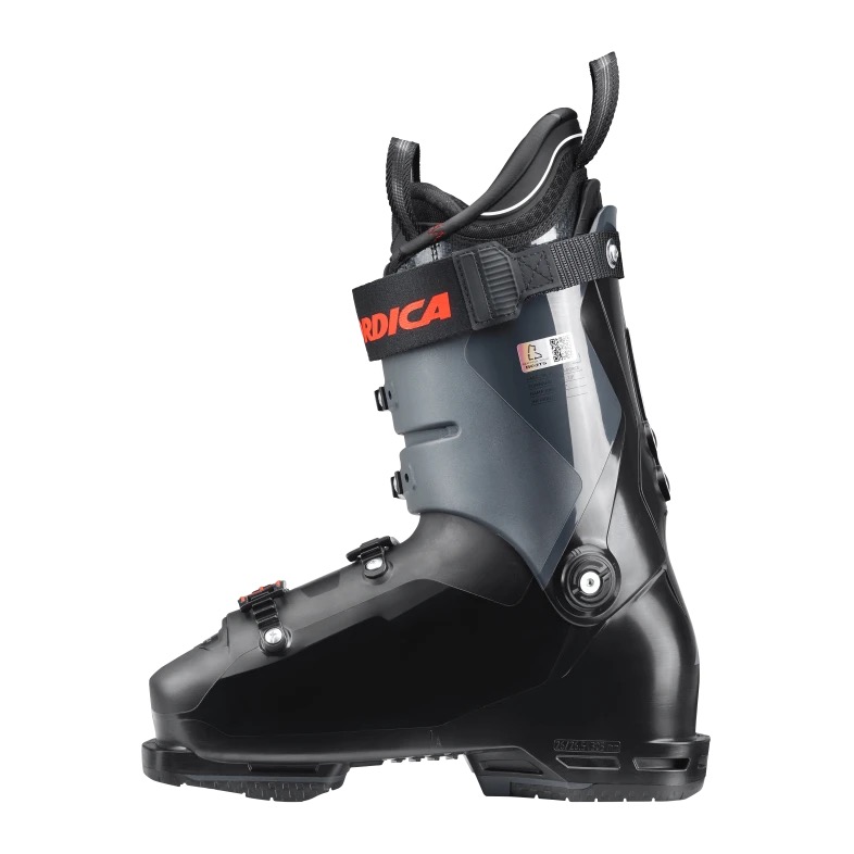 Schwarzer Skischuh der Marke Nordica in Seitenansicht. Zu sehen sind Schnallen, Gurtband mit Markenlogo und Innenschuh.