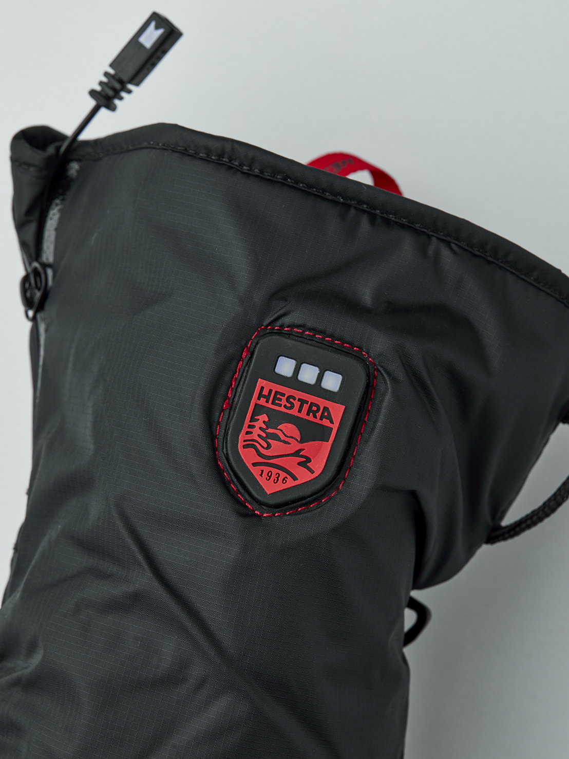 Gros plan sur une doublure de gant chauffante noire de la marque Hestra avec port USB et logo.