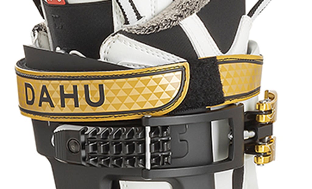 Dahu Ecorce Skischuh Detailaufnahme Dahu Ecorce 01X Skischuh in Weiss-Gold mit schwarzem Verschluss und goldener "DAHU"-Aufschrift.